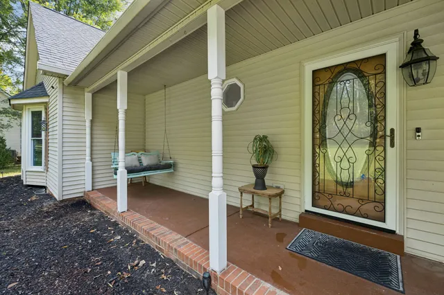 a view of an empty room with wooden floor kitchen view and a window