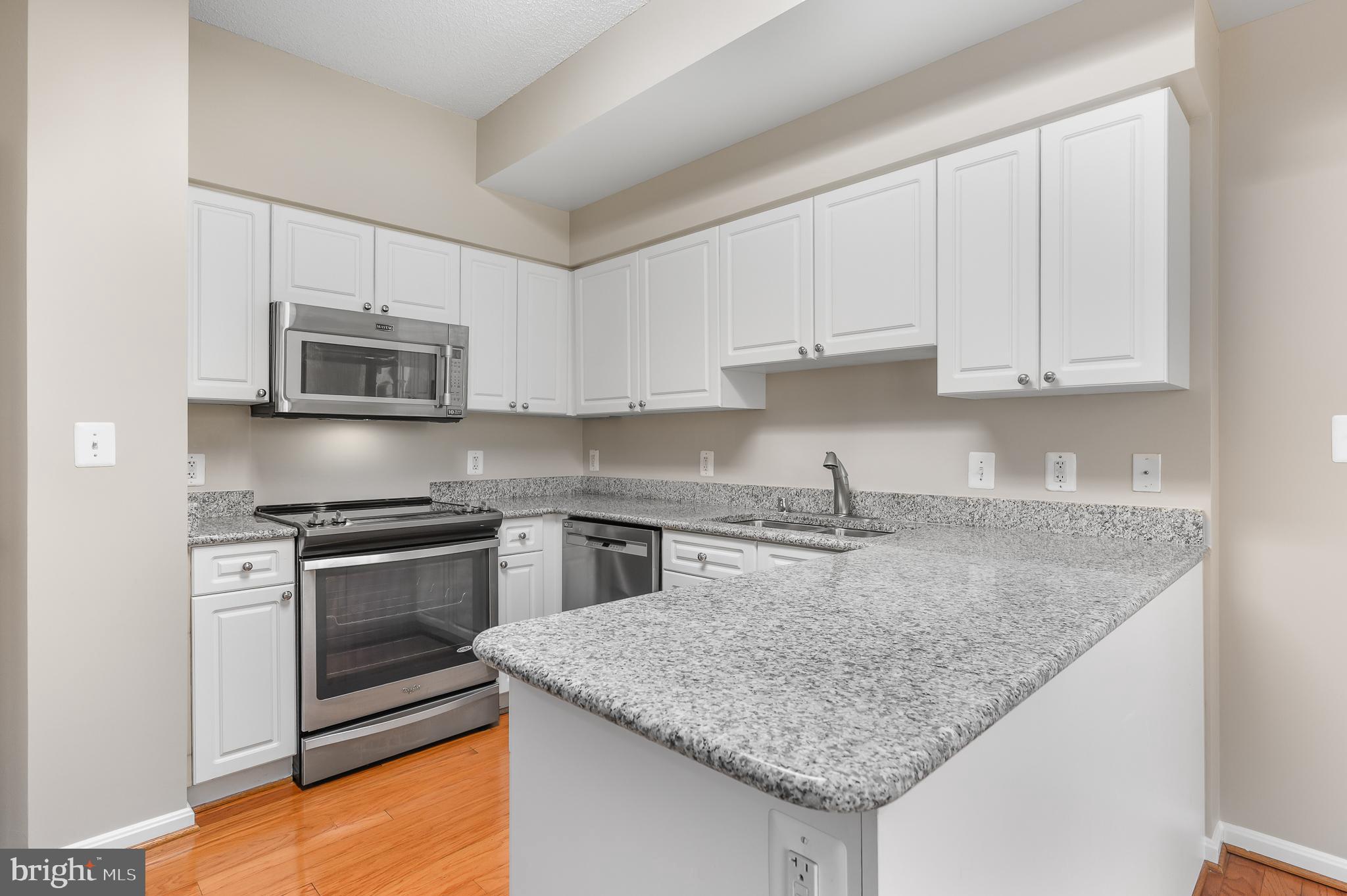 19355 Cypress Ridge Terrace, Unit 219 Leesburg, VA 20176 - Photo 17 of 42 a kitchen with granite countertop a sink dishwasher stove and oven with granite countertops