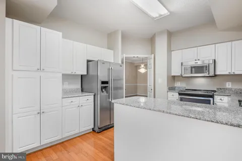 a kitchen with stainless steel appliances granite countertop a refrigerator a stove a sink and white cabinets