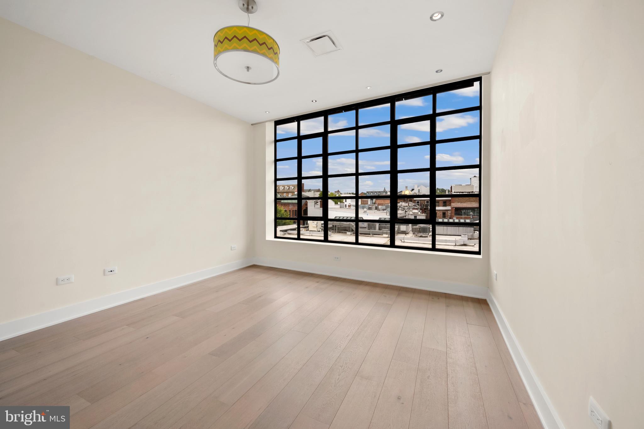 1055 Wisconsin Avenue Northwest, Unit 4E Washington, DC 20007 - Photo 35 of 58 a view of an empty room with a window and wooden floor