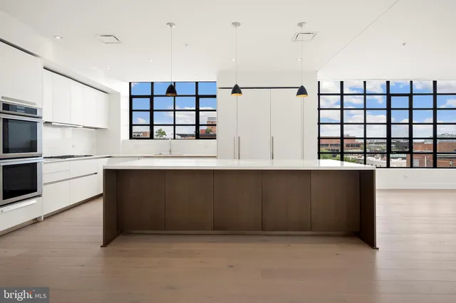 a living room with stainless steel appliances kitchen island granite countertop furniture and a wooden floor