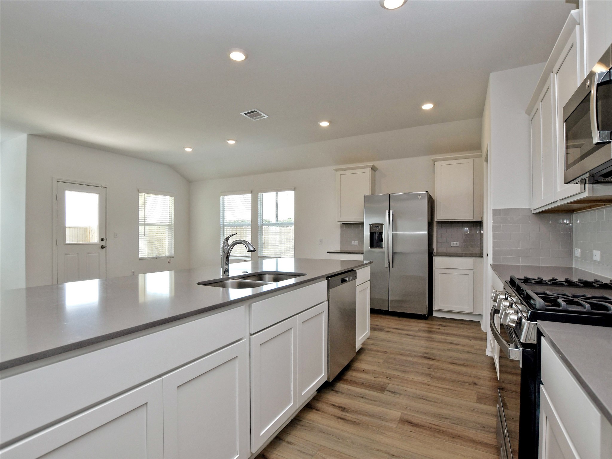 229 Vortex Pass Kyle, TX 78640 - Photo 11 of 32 a kitchen with stainless steel appliances granite countertop refrigerator a sink dishwasher a stove and a refrigerator with wooden floor