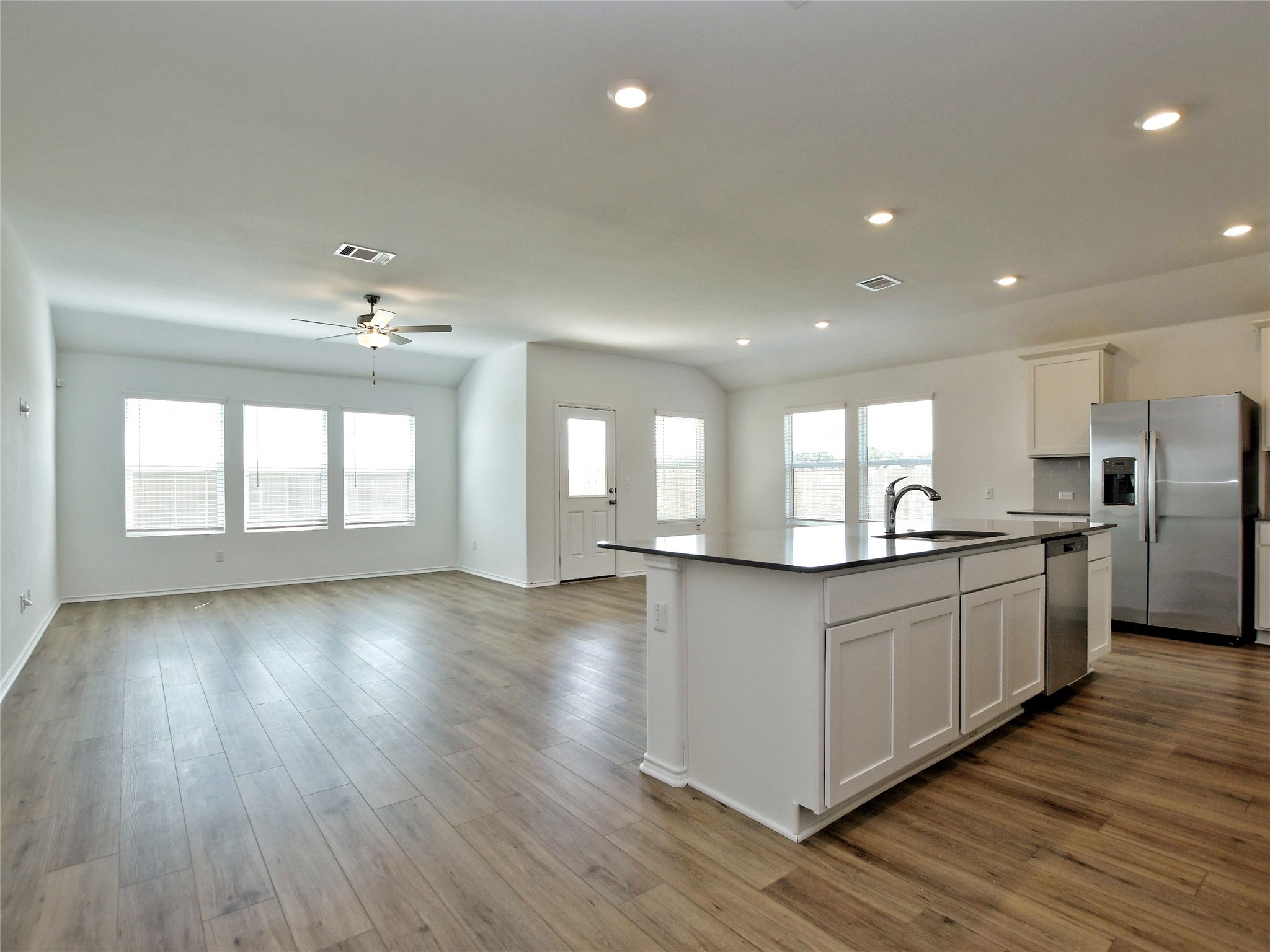 229 Vortex Pass Kyle, TX 78640 - Photo 5 of 32 a kitchen with stainless steel appliances granite countertop a refrigerator a sink dishwasher a stove and a large countertops with wooden floor