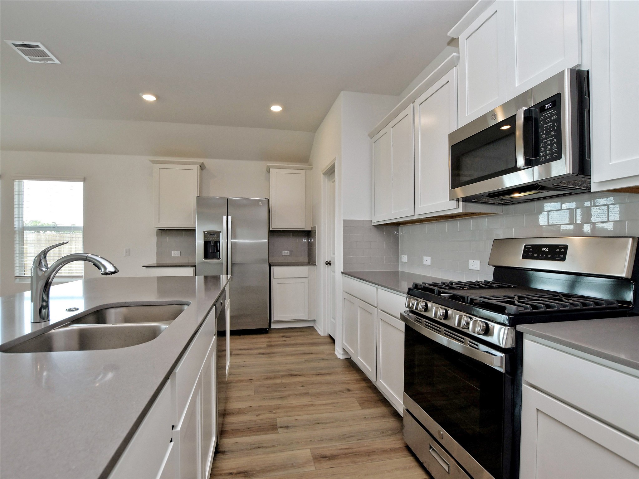 229 Vortex Pass Kyle, TX 78640 - Photo 10 of 32 a kitchen with stainless steel appliances granite countertop a sink a stove top oven and refrigerator