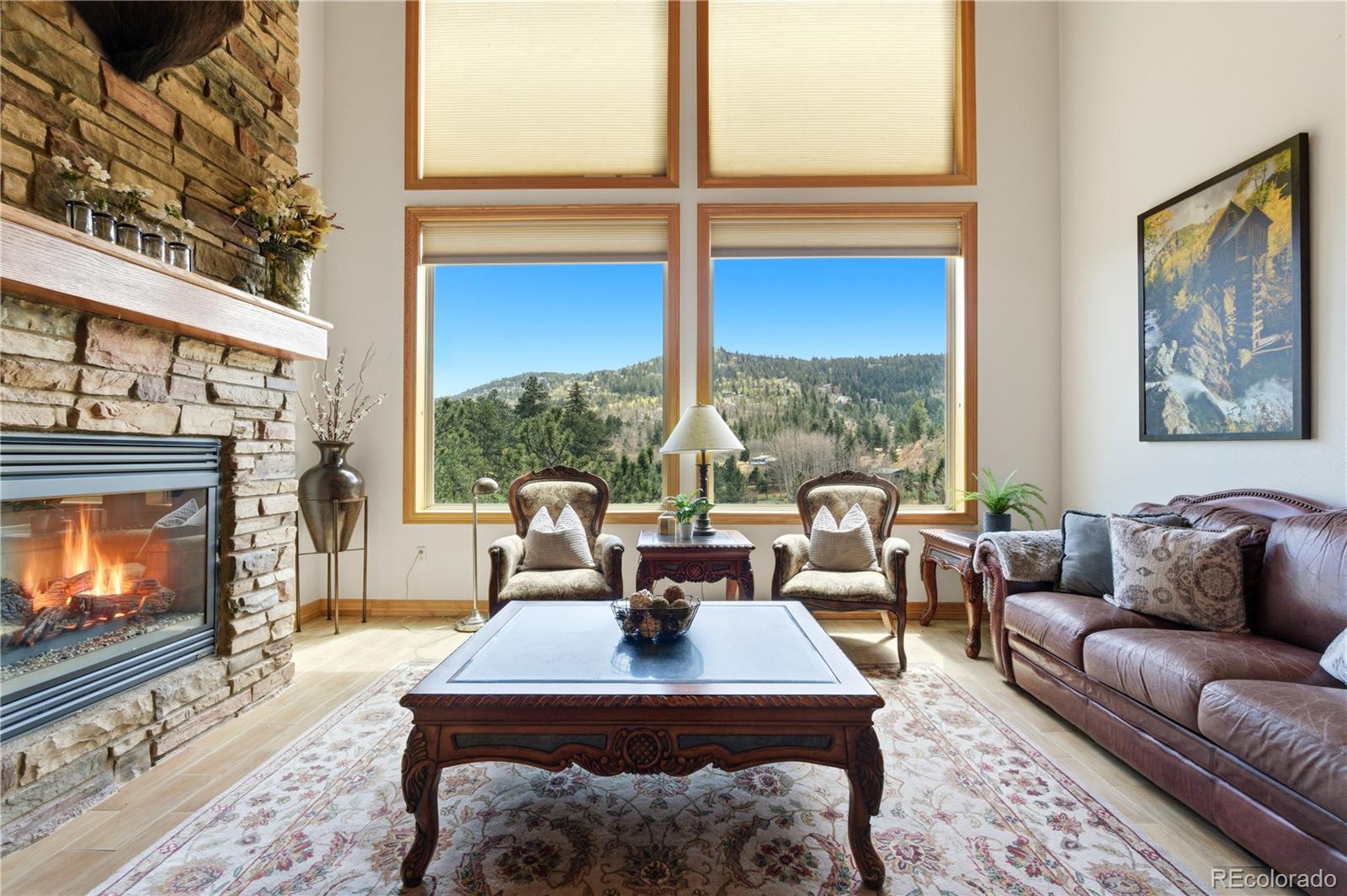 9659 South Turkey Creek Road Morrison, CO 80465 - Photo 2 of 49 a living room with furniture a fireplace and floor to ceiling windows