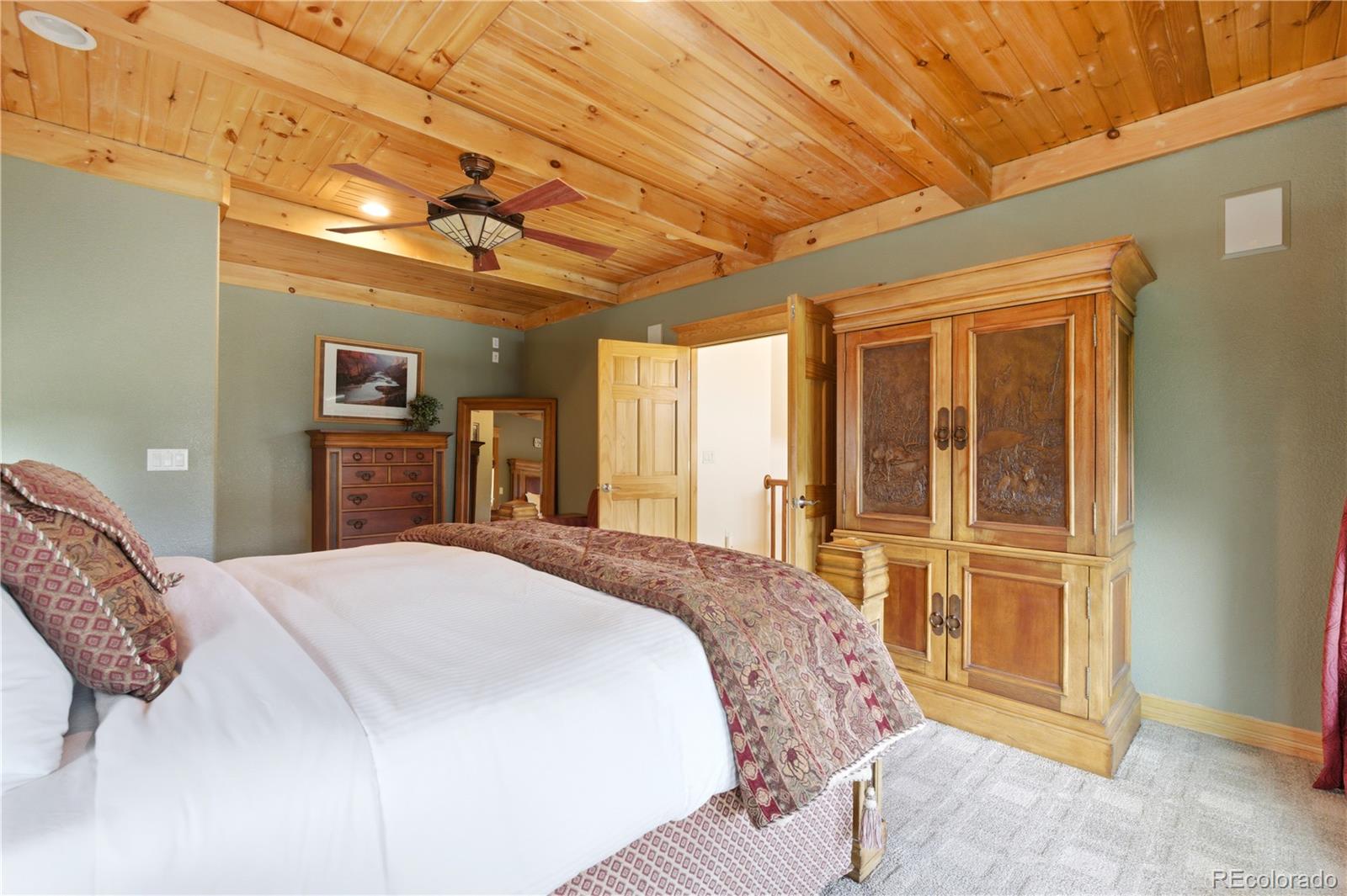 9659 South Turkey Creek Road Morrison, CO 80465 - Photo 29 of 49 a spacious bedroom with a large bed and dresser