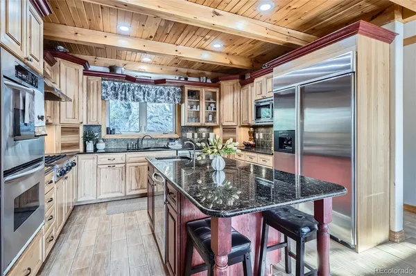 a kitchen with stainless steel appliances granite countertop a stove a sink and dishwasher refrigerator with wooden floor