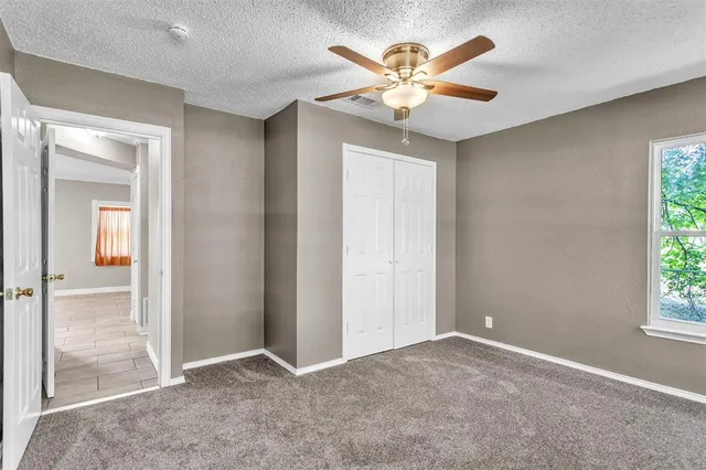 an empty room that has a chandelier fan and windows