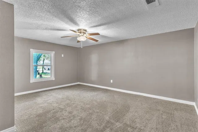 an empty room with windows and fan