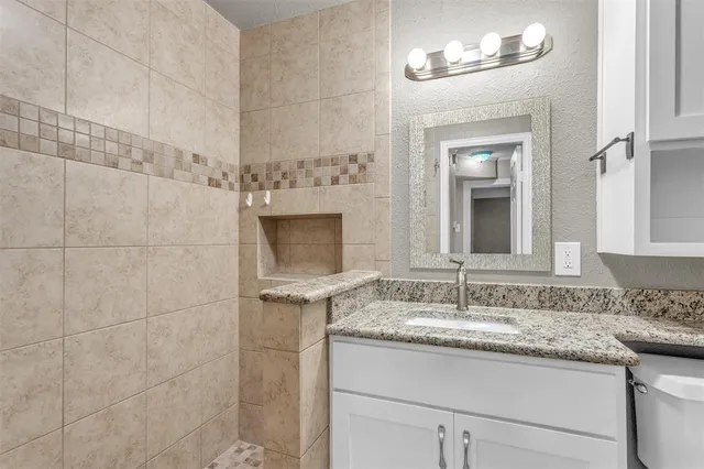 a bathroom with a granite countertop sink a mirror and a shower