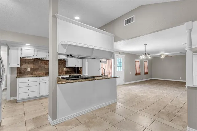 a kitchen with stainless steel appliances granite countertop a stove top oven a sink a refrigerator and white cabinets