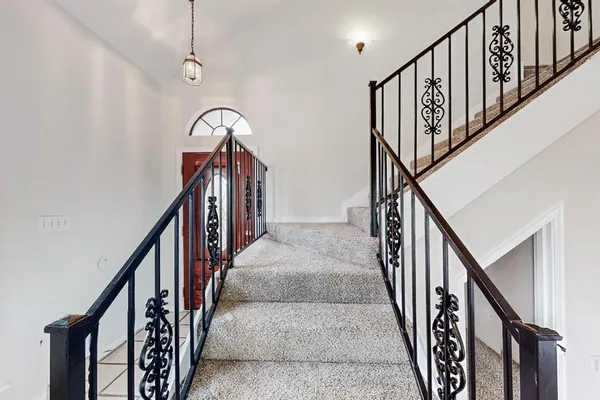 a view of staircase with lots of frames on wall and wooden floor