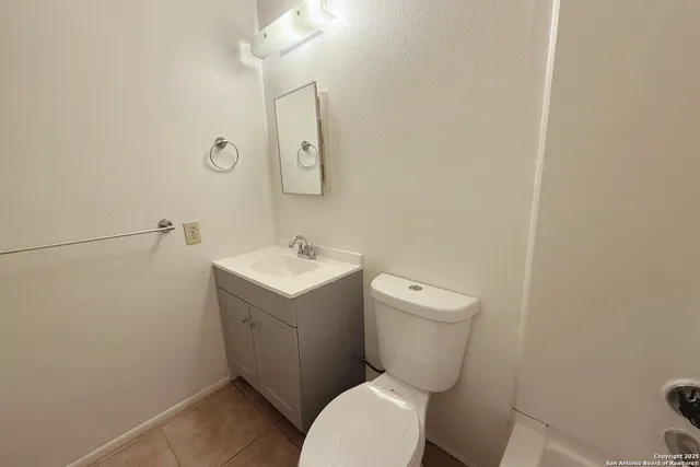 a white toilet sitting next to a white sink and vanity