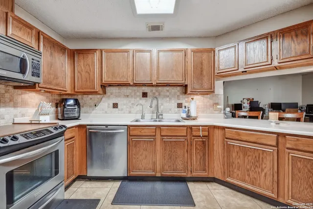 a kitchen with cabinets appliances a sink and a window