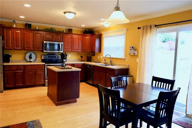 a kitchen with stainless steel appliances granite countertop a stove a sink dishwasher a dining table and chairs
