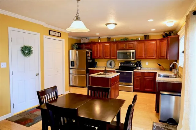 a kitchen with stainless steel appliances granite countertop a stove refrigerator a dining table and chairs