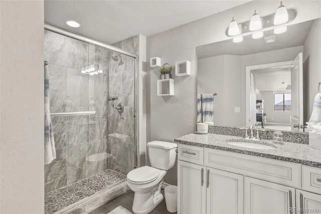 a bathroom with a granite countertop sink toilet a mirror and shower