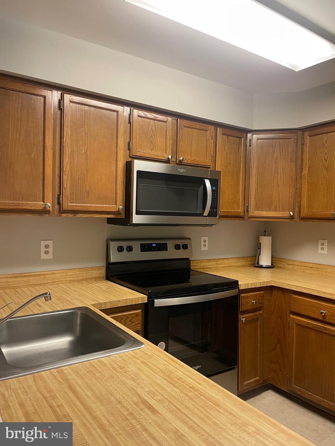 7828 Harrowgate Circle, Unit C Springfield, VA 22152 - Photo 3 of 11 a kitchen with stainless steel appliances granite countertop a sink and a stove top oven with wooden floor