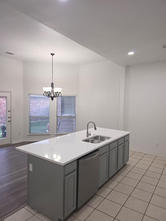 8047 New Kent Road Frisco, TX 75035 - Photo 4 of 27 Kitchen island featuring a white countertop, dual basin sink with gooseneck faucet, and integrated stainless steel dishwasher