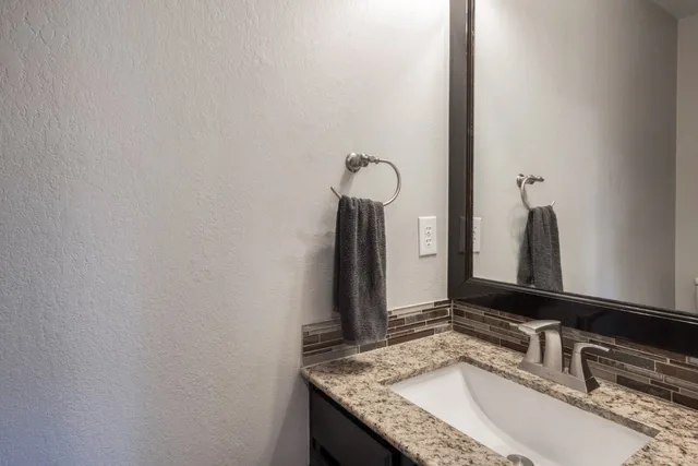 a bathroom with a granite countertop sink and a mirror