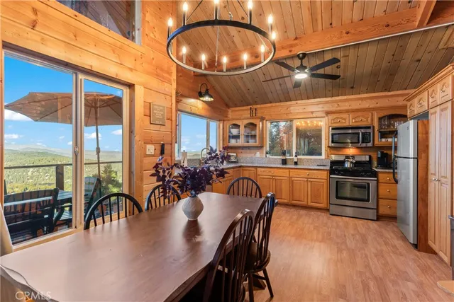 a kitchen with stainless steel appliances granite countertop a stove a refrigerator a dining table and chairs with wooden floor