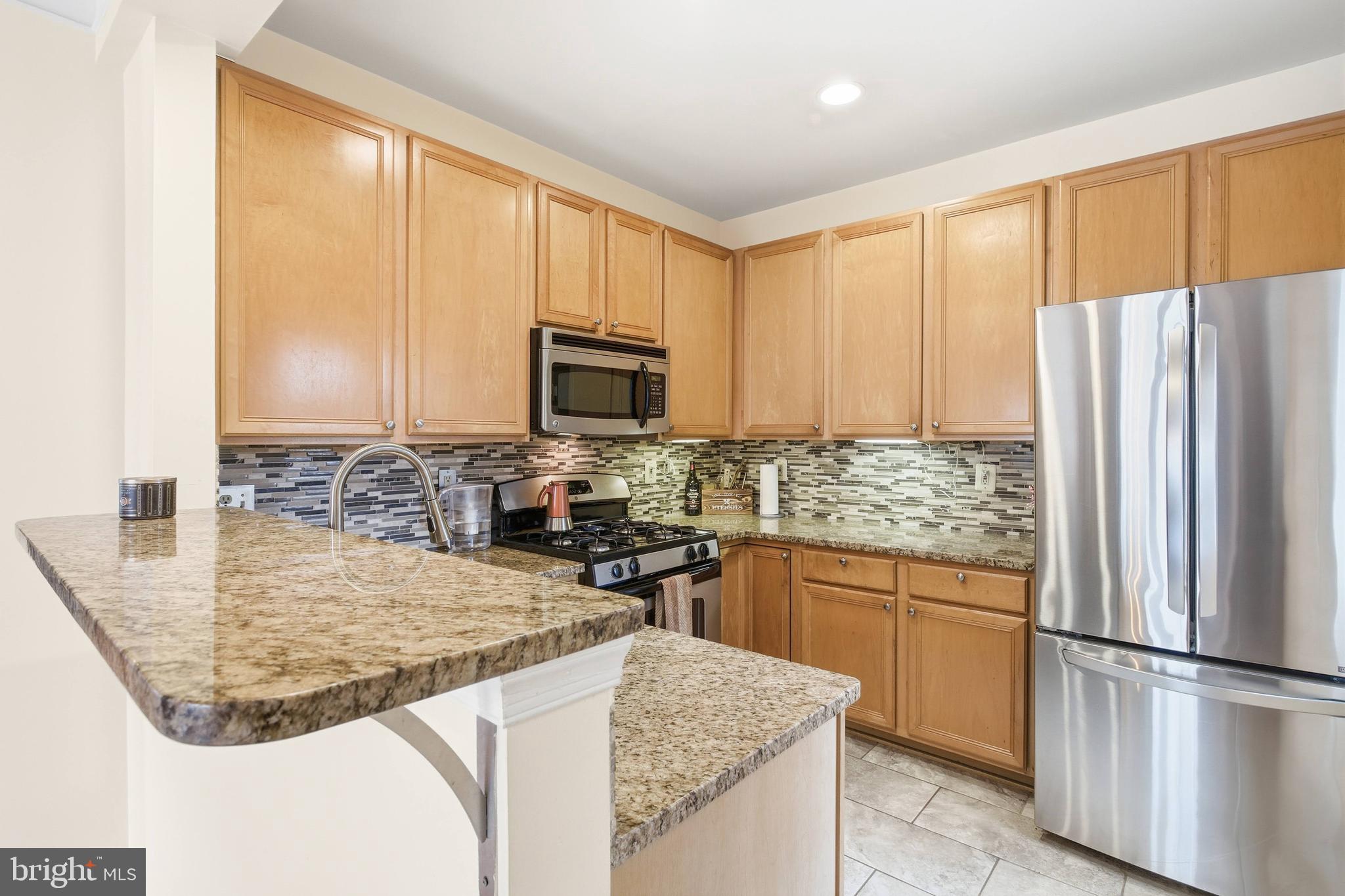 11302 Westbrook Mill Lane, Unit 204 Fairfax, VA 22030 - Photo 14 of 30 a kitchen with kitchen island granite countertop a refrigerator stove microwave and sink