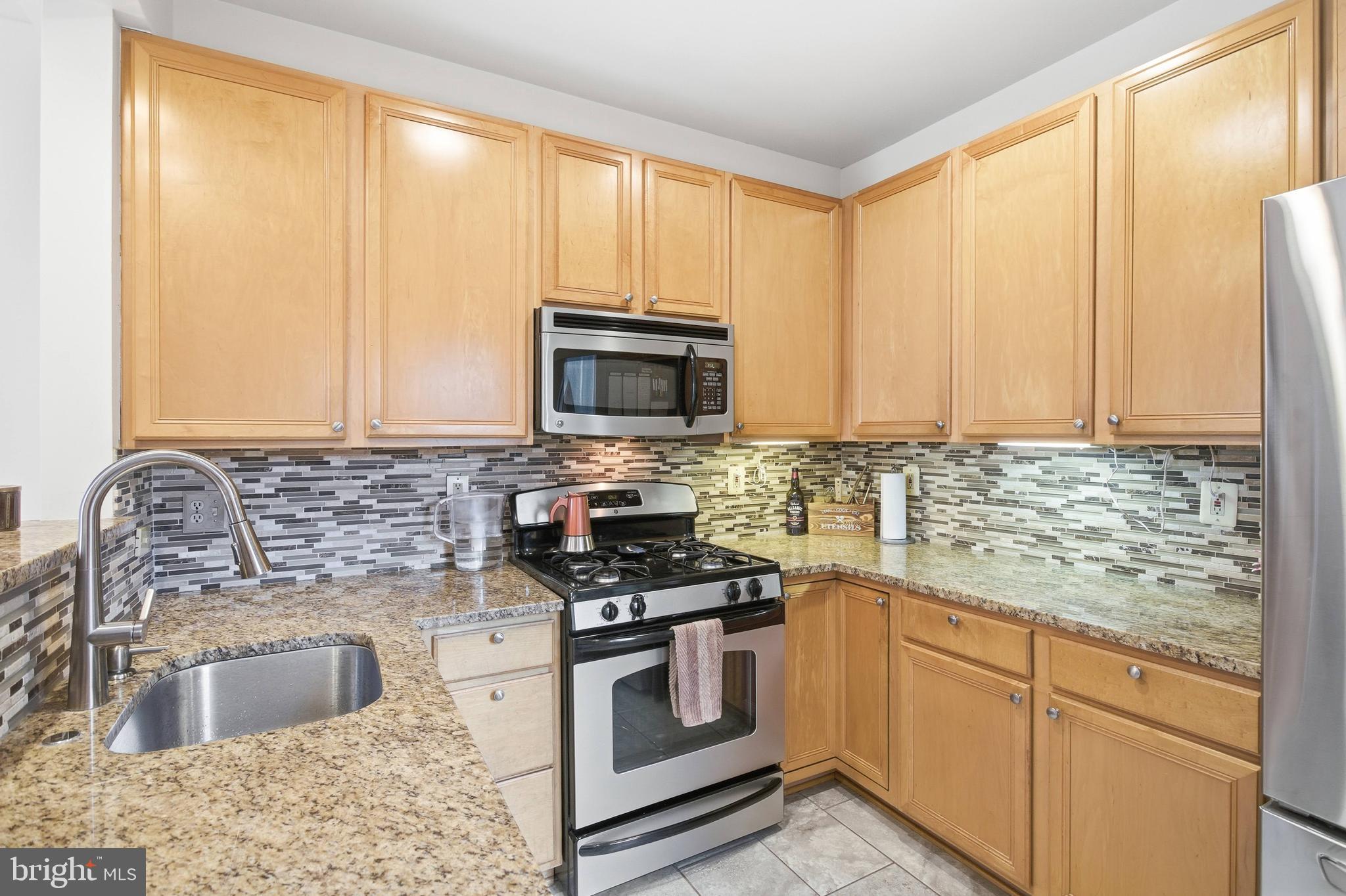 11302 Westbrook Mill Lane, Unit 204 Fairfax, VA 22030 - Photo 16 of 30 a kitchen with granite countertop a stove a sink and a microwave