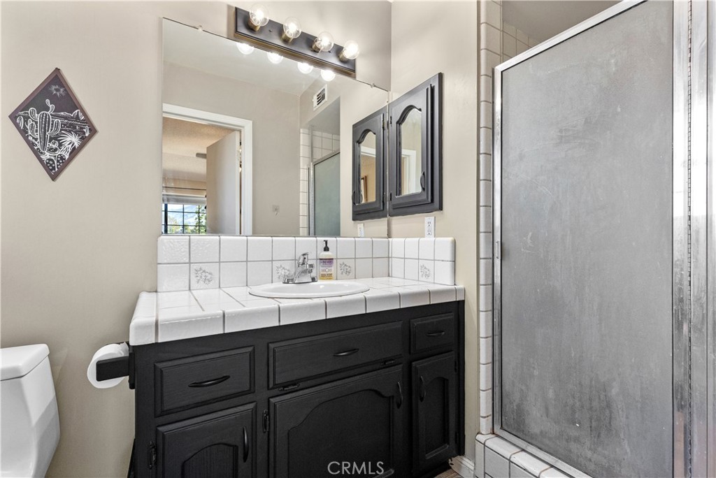 21921 Fig Court Tehachapi, CA 93561 - Photo 29 of 44 a bathroom with a sink a mirror a vanity and shower