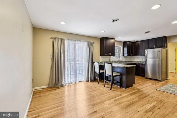 a kitchen with stainless steel appliances kitchen island granite countertop a refrigerator a stove a sink dishwasher with a dining table and chairs