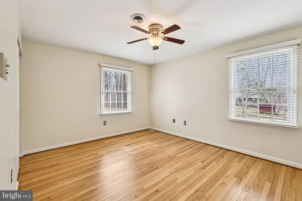 a view of empty room with wooden floor and fan
