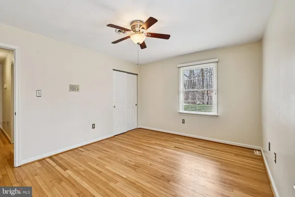 an empty room with wooden floor ceiling fan and windows