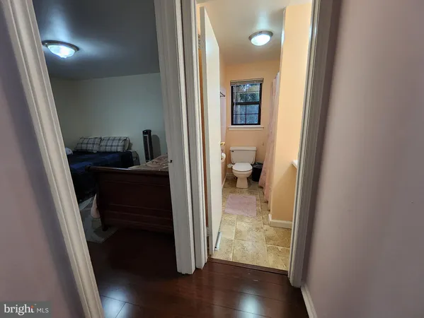 a view of a hallway with wooden floor and a bathroom