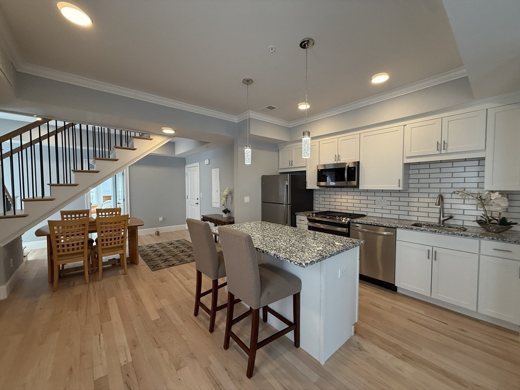 7 Waumbeck Street, Unit 3 Boston, MA 02121 - Photo 10 of 21 a kitchen with stainless steel appliances granite countertop a table chairs sink and cabinets