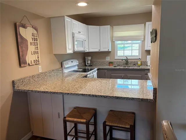a kitchen with granite countertop kitchen island a table and chairs in it