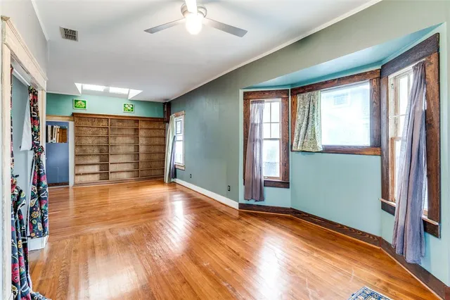 a view of an empty room with window and hardwood floor