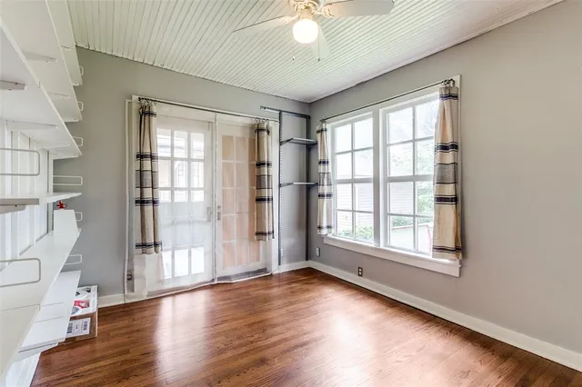 an empty room with wooden floor and windows with curtains view