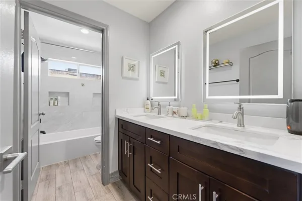 a bathroom with a tub a sink double vanity and mirror