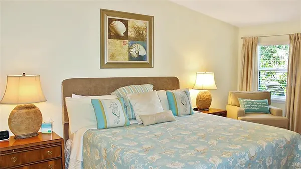 a large bed sitting in a bedroom next to a window and a lamp