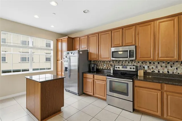 a kitchen with stainless steel appliances granite countertop a stove top oven a refrigerator a sink and dishwasher with white cabinets