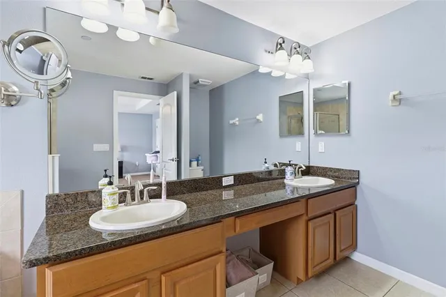 a bathroom with a granite countertop double vanity and a mirror
