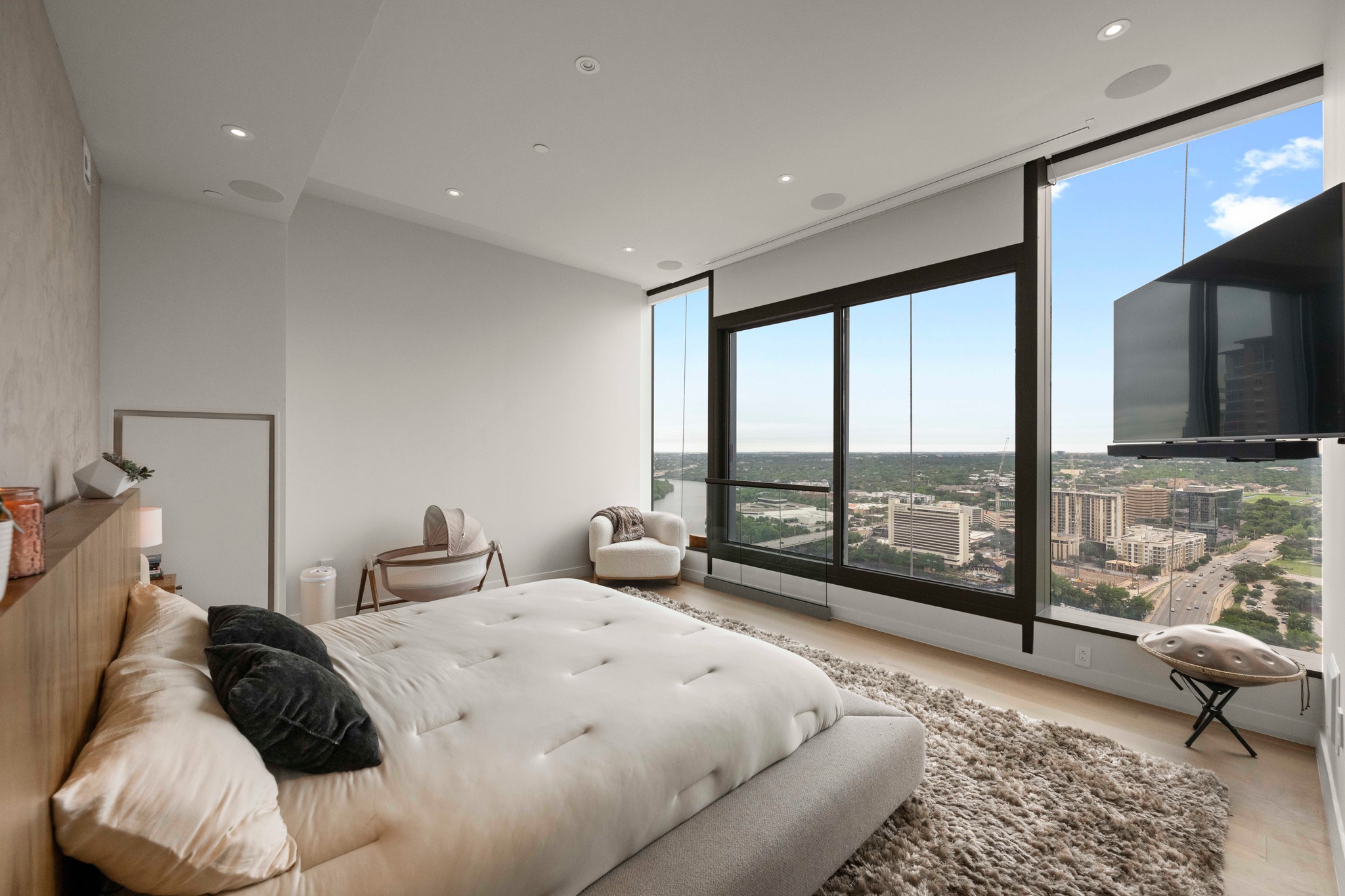 210 Lavaca Street, Unit 2706 Austin, TX 78701 - Photo 14 of 32 Expansive window wall with panoramic cityscape, recessed lighting, integrated ceiling speakers, wood-finish flooring, and a textured accent wall