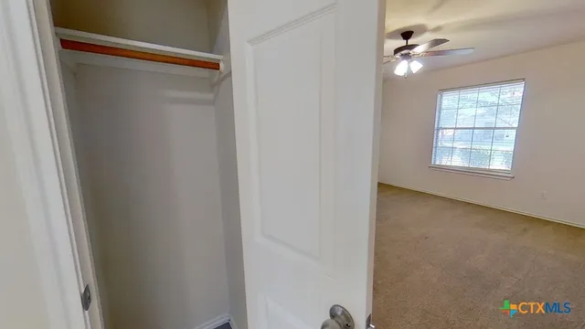 an empty room with windows and ceiling fan