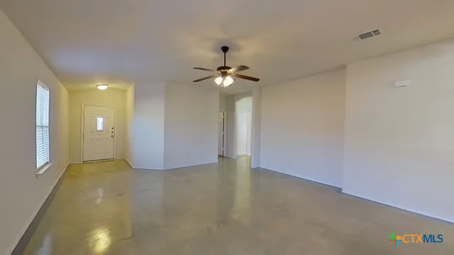 a view of an empty room with a chandelier fan