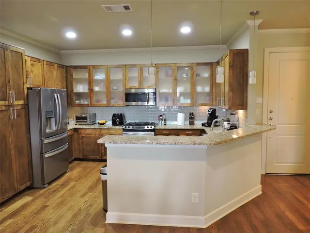 a kitchen with stainless steel appliances granite countertop a refrigerator a sink a stove and a refrigerator