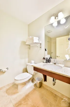 a bathroom with a granite countertop sink a toilet and a mirror