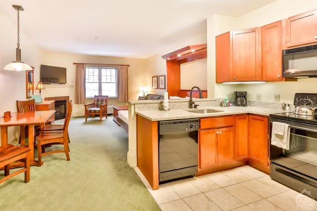 a kitchen with stainless steel appliances granite countertop dining table chairs sink and cabinets