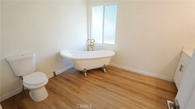 a bathroom with a sink a toilet and a wooden floor