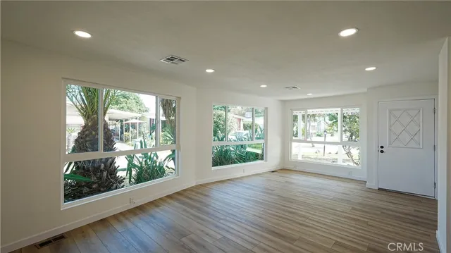 a view of an empty room with wooden floor and a window