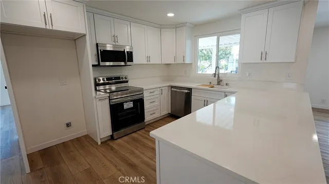 a kitchen with granite countertop white cabinets and black stainless steel appliances