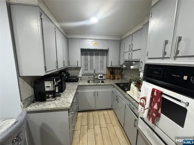 a kitchen with granite countertop a sink a stove and cabinets
